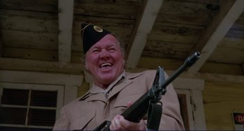 Movie still from “Eat My Dust” (1976), directed by Charles B. Griffith – An older man wearing a uniform and holding a rifle; Close Up shot, Low angle