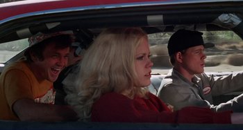 Movie still from “Eat My Dust” (1976), directed by Charles B. Griffith – A woman sitting in the back seat of a car; Medium shot, Over the shoulder angle