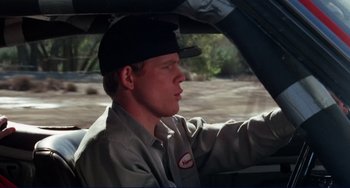 Movie still from “Eat My Dust” (1976), directed by Charles B. Griffith – A man driving a car in the rain; Medium shot, Low angle