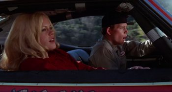 Movie still from “Eat My Dust” (1976), directed by Charles B. Griffith – A man and a woman in the back seat of a car; Medium shot, Low angle