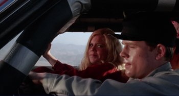 Movie still from “Eat My Dust” (1976), directed by Charles B. Griffith – A man and a woman in the drivers seat of a car; Close Up shot, Low angle
