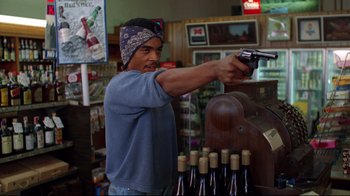 Movie still from “Eating Raoul” (1982), directed by Paul Bartel – A man holding a gun while standing in a store; Medium shot, Low angle