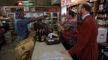 Movie still from “Eating Raoul” (1982), directed by Paul Bartel – Three men are standing at a counter in a liquor store; Medium shot, Over the shoulder angle