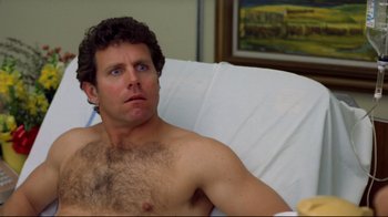 Movie still from “Eating Raoul” (1982), directed by Paul Bartel – A shirtless man sitting in a hospital bed; Close Up shot, High angle