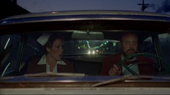 Movie still from “Eating Raoul” (1982), directed by Paul Bartel – A man and a woman sitting in the back of a car; Medium shot, Low angle