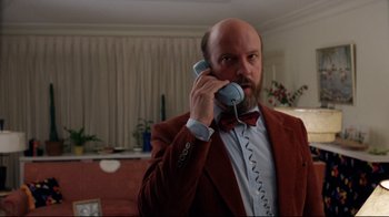 Movie still from “Eating Raoul” (1982), directed by Paul Bartel – A man in a red jacket is holding a phone to his ear; Medium shot, Low angle
