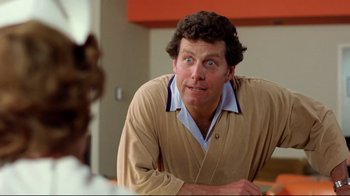 Movie still from “Eating Raoul” (1982), directed by Paul Bartel – A person sitting in front of a cat; Close Up shot, Low angle