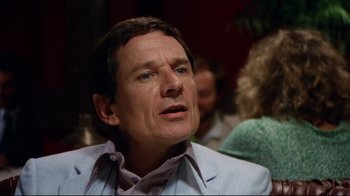 Movie still from “Eating Raoul” (1982), directed by Paul Bartel – A person wearing a suit; Close Up shot, Over the shoulder angle