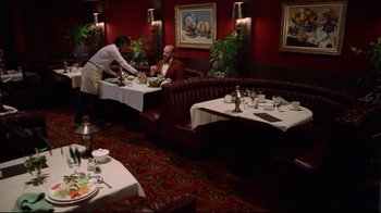 Movie still from “Eating Raoul” (1982), directed by Paul Bartel – Two people sitting at a table in a restaurant; Wide shot, High angle