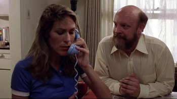 Movie still from “Eating Raoul” (1982), directed by Paul Bartel – A man and a woman sitting at a table talking on a phone; Close Up shot, Low angle