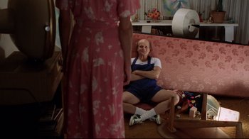 Movie still from “Eating Raoul” (1982), directed by Paul Bartel – An older man sitting on the ground in front of a woman; Wide shot, High angle