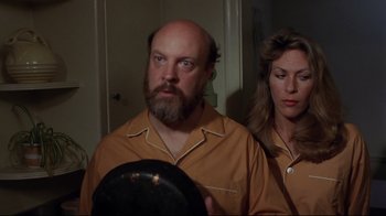 Movie still from “Eating Raoul” (1982), directed by Paul Bartel – A man and a woman are looking at a plate; Medium shot, High angle