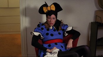 Movie still from “Eating Raoul” (1982), directed by Paul Bartel – A woman dressed as minnie mouse sitting in a chair; Medium shot, Low angle