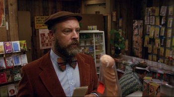 Movie still from “Eating Raoul” (1982), directed by Paul Bartel – A man in a brown jacket and a bow tie; Close Up shot, Over the shoulder angle