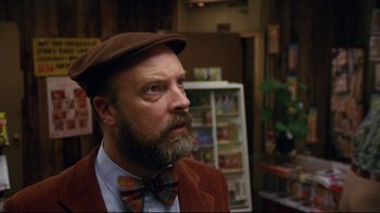 Movie still from “Eating Raoul” (1982), directed by Paul Bartel – A man with a beard wearing a hat and bow tie; Close Up shot, Over the shoulder angle