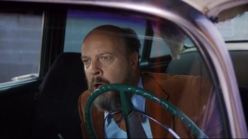 Movie still from “Eating Raoul” (1982), directed by Paul Bartel – A man with a beard driving a car; Medium shot, Low angle