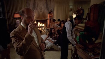 Movie still from “Eating Raoul” (1982), directed by Paul Bartel – A group of people sitting around a living room; Wide shot, Over the shoulder angle