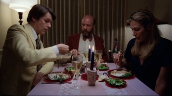 Movie still from “Eating Raoul” (1982), directed by Paul Bartel – A group of people sitting around a dinner table; Medium shot, High angle