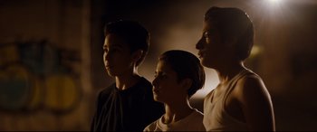 Movie still from “El Chicano” (2018), directed by Ben Hernandez Bray – Three young men standing next to each other in the dark; Medium shot, Low angle