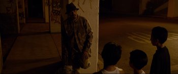 Movie still from “El Chicano” (2018), directed by Ben Hernandez Bray – A man standing next to a wall with a hat on; Medium shot, Over the shoulder angle