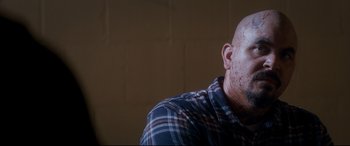 Movie still from “El Chicano” (2018), directed by Ben Hernandez Bray – A bald man wearing a plaid shirt with a beard; Close Up shot, Over the shoulder angle