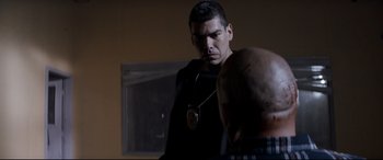 Movie still from “El Chicano” (2018), directed by Ben Hernandez Bray – A man with a medal in front of a mirror; Medium shot, Over the shoulder angle