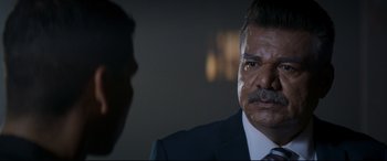Movie still from “El Chicano” (2018), directed by Ben Hernandez Bray – A person wearing a suit and tie; Close Up shot, Over the shoulder angle