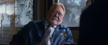 Movie still from “El Chicano” (2018), directed by Ben Hernandez Bray – An older man wearing a blue jacket and a tie; Close Up shot, Over the shoulder angle