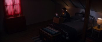 Movie still from “El Chicano” (2018), directed by Ben Hernandez Bray – A man sitting on the floor in a dark room reading; Wide shot, High angle
