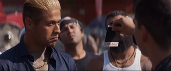 Movie still from “El Chicano” (2018), directed by Ben Hernandez Bray – A person taking a picture of a man with blonde hair; Close Up shot, Over the shoulder angle