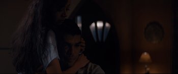 Movie still from “El Chicano” (2018), directed by Ben Hernandez Bray – A man and a woman embracing in a dark room; Medium shot, Low angle