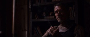 Movie still from “El Chicano” (2018), directed by Ben Hernandez Bray – An older man smoking a cigarette in a dark room; Close Up shot, Over the shoulder angle
