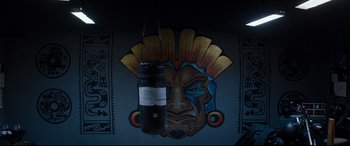 Movie still from “El Chicano” (2018), directed by Ben Hernandez Bray – A punching bag hanging in front of a wall with an image on it; Extreme Close Up shot, Overhead angle