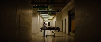 Movie still from “El Chicano” (2018), directed by Ben Hernandez Bray – A person standing next to a bed in a room; Extreme Wide shot, Low angle