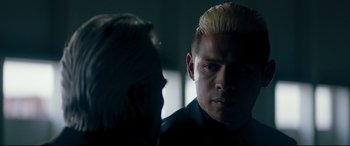 Movie still from “El Chicano” (2018), directed by Ben Hernandez Bray – A man with blonde hair is looking at another man in a dark room; Close Up shot, Over the shoulder angle