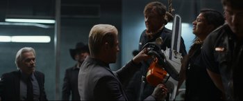 Movie still from “El Chicano” (2018), directed by Ben Hernandez Bray – A man in a black suit is holding an orange object; Medium shot, Over the shoulder angle