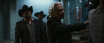 Movie still from “El Chicano” (2018), directed by Ben Hernandez Bray – A man with a white hair and a black suit; Close Up shot, Over the shoulder angle