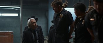 Movie still from “El Chicano” (2018), directed by Ben Hernandez Bray – A man in a suit and tie next to another man in a suit and tie; Medium shot, Over the shoulder angle