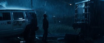 Movie still from “El Chicano” (2018), directed by Ben Hernandez Bray – A man standing in the rain holding a fire hydrant; Wide shot, Low angle