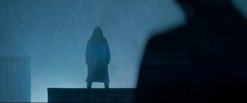 Movie still from “El Chicano” (2018), directed by Ben Hernandez Bray – A person standing in the rain in a long coat; Wide shot, Low angle