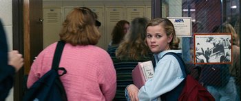 Movie still from “Election” (1999), directed by Alexander Payne – A woman holding a book in front of a group of people; Medium shot, Low angle