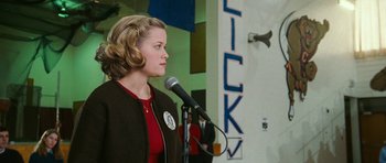 Movie still from “Election” (1999), directed by Alexander Payne – A woman is speaking into a microphone at a political event; Medium shot, Low angle