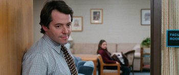 Movie still from “Election” (1999), directed by Alexander Payne – A man wearing a tie standing in front of a woman in a chair; Close Up shot, Over the shoulder angle