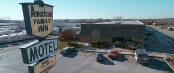Movie still from “Election” (1999), directed by Alexander Payne – Cars parked in a parking lot next to a building; Extreme Wide shot, High angle