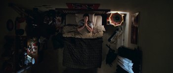 Movie still from “Election” (1999), directed by Alexander Payne – A man laying in a bed in a room; Wide shot, Overhead angle