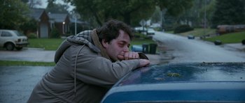 Movie still from “Election” (1999), directed by Alexander Payne – A man leaning on the hood of a blue car; Medium shot, High angle