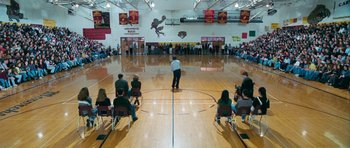 Movie still from “Election” (1999), directed by Alexander Payne – A group of people sitting in a gym on a basketball court; Extreme Wide shot, High angle