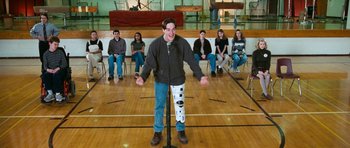 Movie still from “Election” (1999), directed by Alexander Payne – A man standing in front of a group of people in a gym; Wide shot, High angle