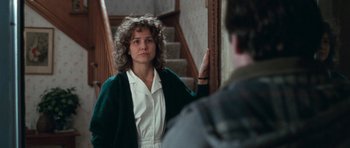 Movie still from “Election” (1999), directed by Alexander Payne – A woman standing in front of a mirror in front of a staircase; Medium shot, Over the shoulder angle