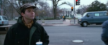 Movie still from “Election” (1999), directed by Alexander Payne – A man holding a cup while standing on the side of the road; Medium shot, Low angle